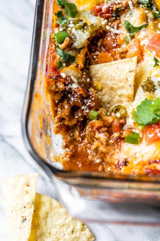 Grab some chips and dig into this cheesy, Baked Mexican Layer Dip made with spiced ground turkey, refried beans, salsa, green chilies, tomatoes, cheese and avocado.