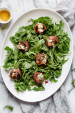 Prosciutto Wrapped Figs with Blue Cheese served on a bed of baby arugula with a light vinaigrette. A delicious combination of salt, acid and sweet.
