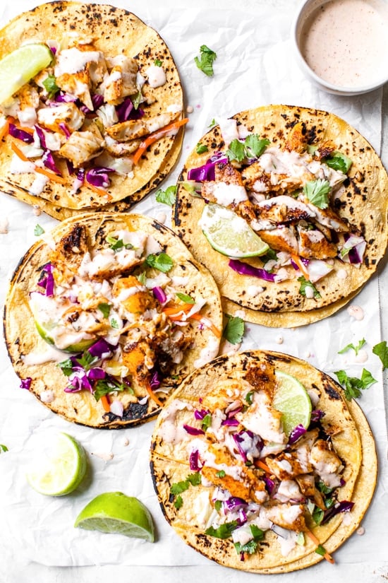 This easy, healthy fish taco recipe is made with cod seasoned with a chili-lime cumin rub topped with slaw – no breading, no frying!