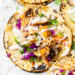 This easy, healthy fish taco recipe is made with cod seasoned with a chili-lime cumin rub topped with slaw – no breading, no frying!