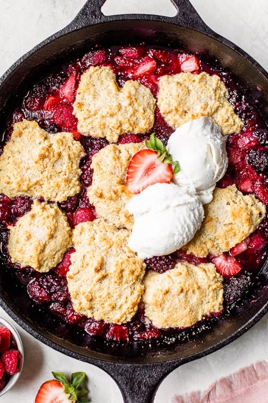 Skillet Mixed Berry Buttermilk Cobbler is made with blackberries, raspberries, and strawberries covered with a delicious biscuit topping and baked in a cast iron skillet.