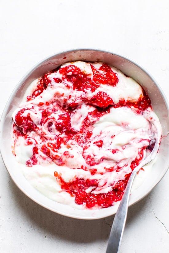 mashed raspberries with yogurt in a bowl