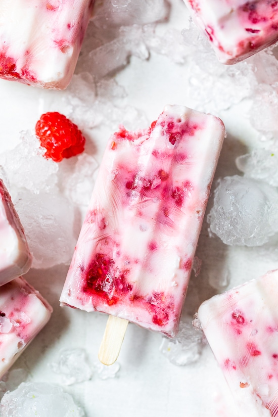 Paletas de helado de yogur de frambuesa sobre hielo.