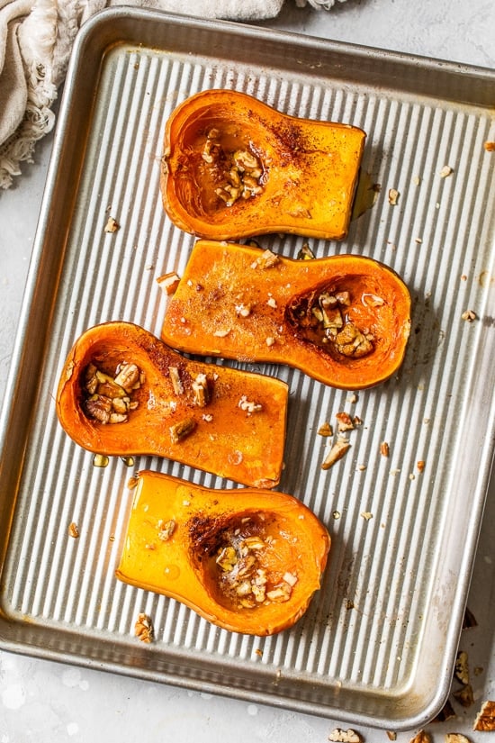Close up of honeynut squash roasted with maple and pecans on a sheet pan.