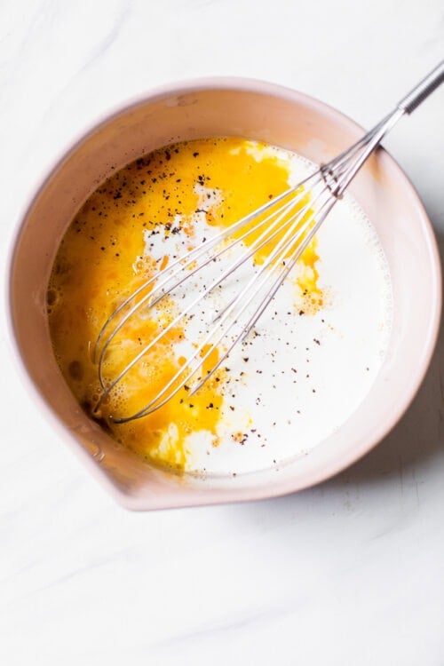 eggs and cream with whisk in a bowl.
