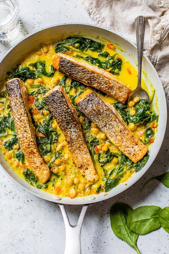 salmon in a skillet with spinach and chickpeas