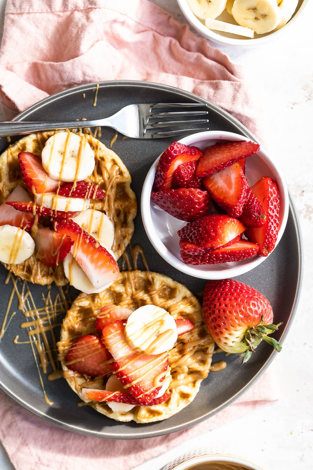 Waffles with strawberries, peanut ،er and bananas.