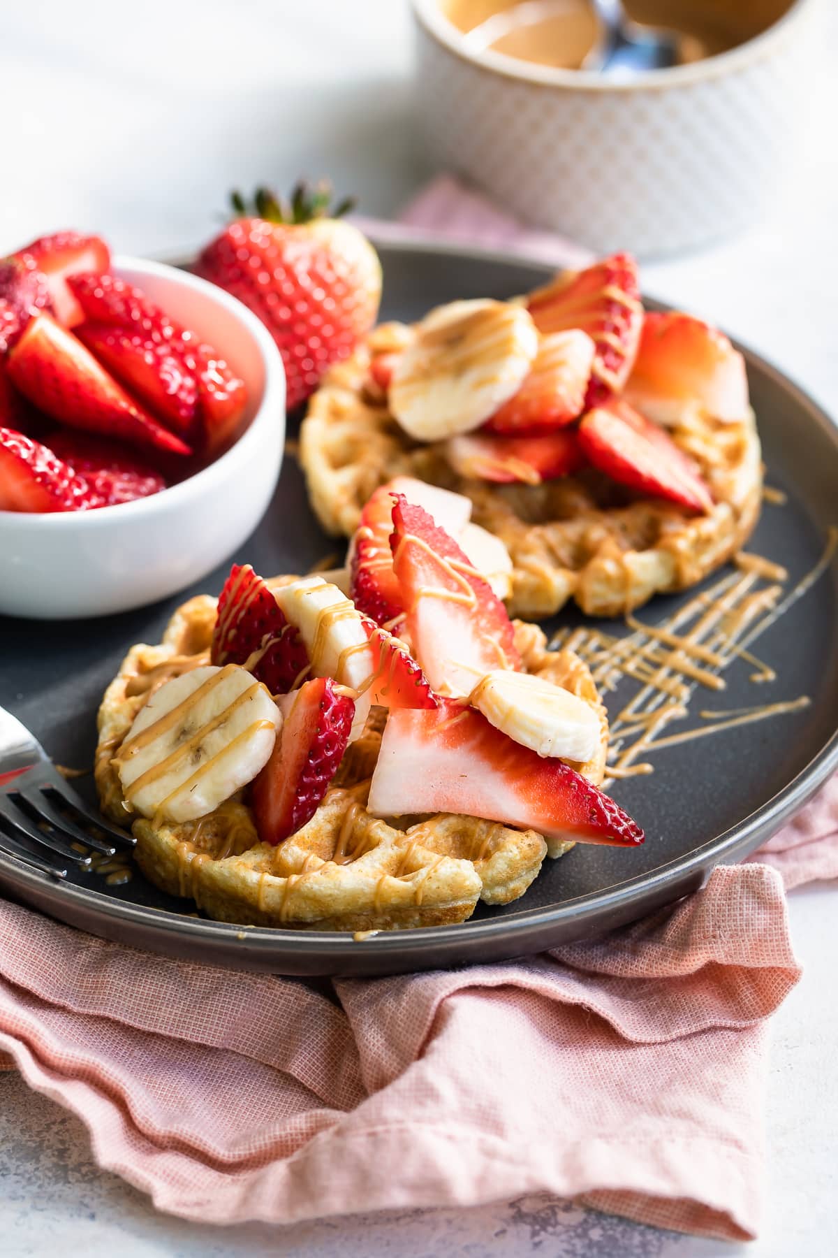 Waffles with strawberries, peanut ،er and bananas.