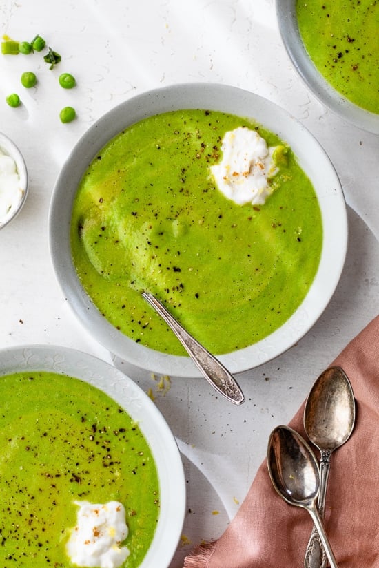 Spring pea soup and fresh herbs in bowls.