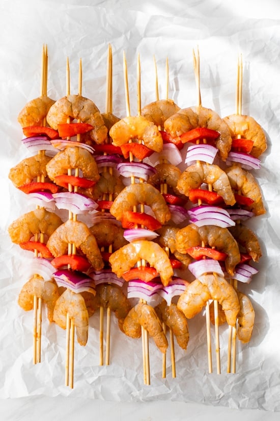 Shrimp skewers with onions, bell peppers and lemon wedges