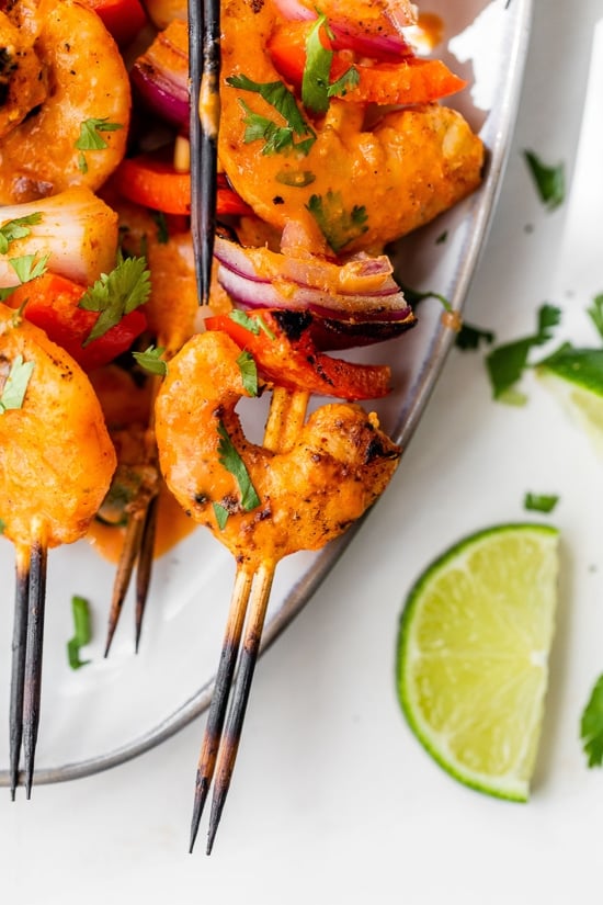 Shrimp skewers with onions, bell peppers and lemon wedges