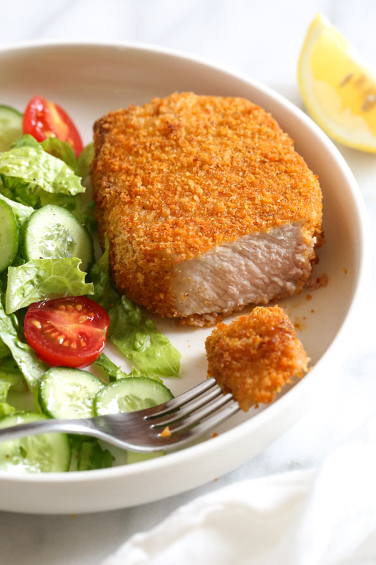 Airfryer breaded pork chops served with lettuce, tomato, cucumber and fork