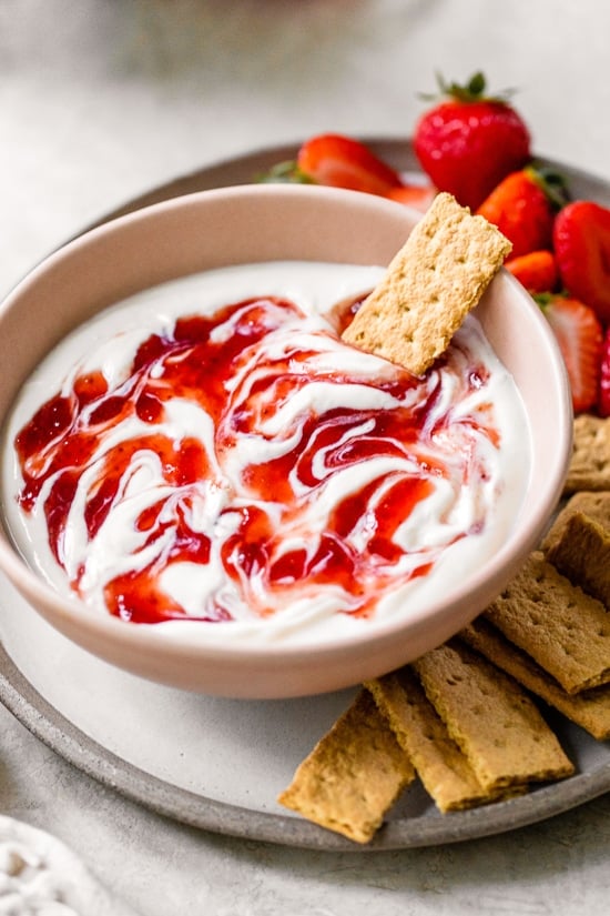 Cheesecake Dip with strawberry preserves swirled on top.