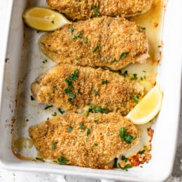 baked breaded chicken breast with lemons in a platter