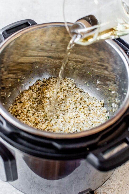 Broth being added to an Instant Pot with risotto