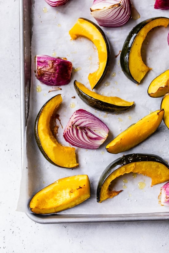 Roasted Acorn Squash and red onion on sheet pan.