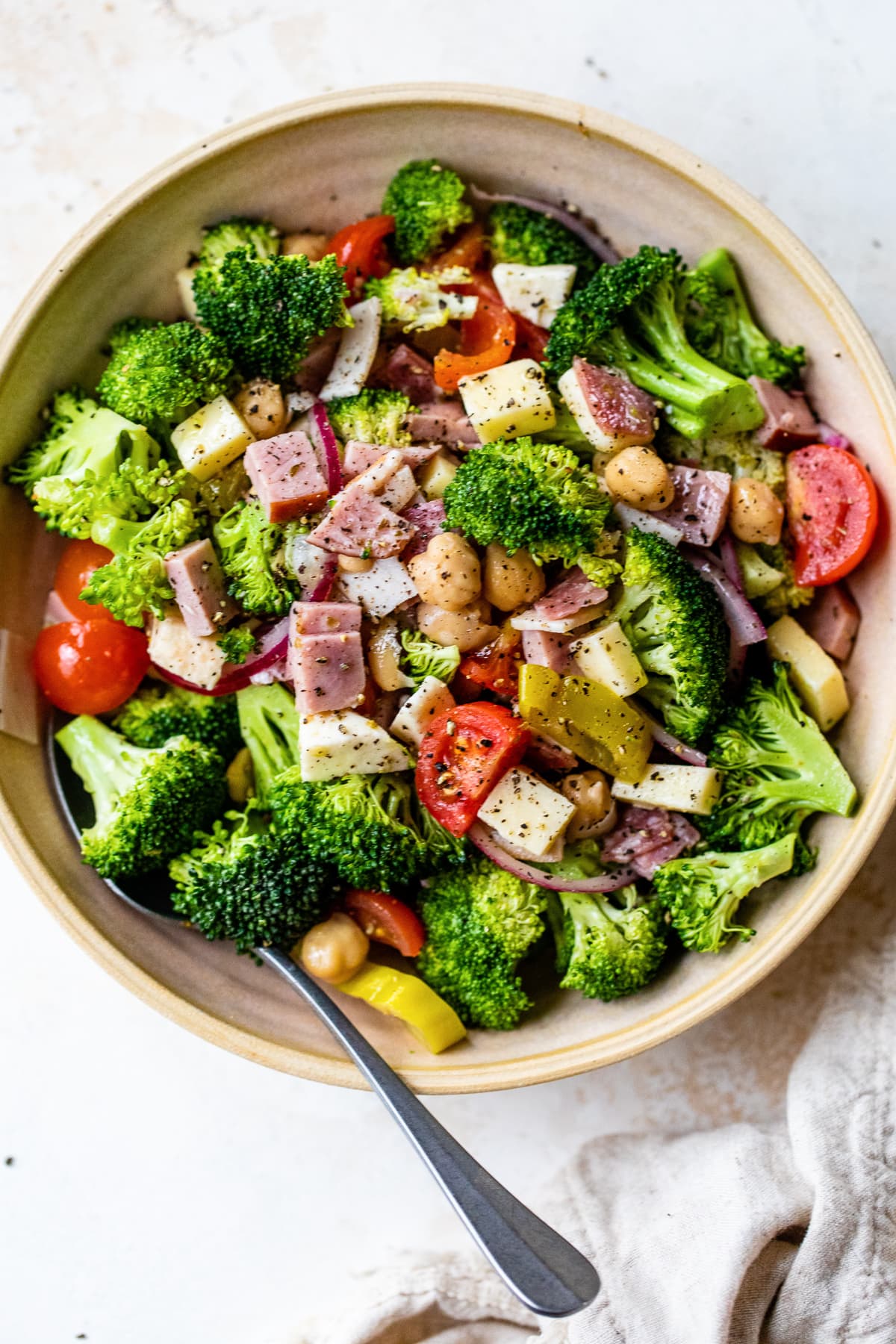 Broccoli, salami, ham, turkey, pepperoncini, mozzarella and provolone in a bowl.