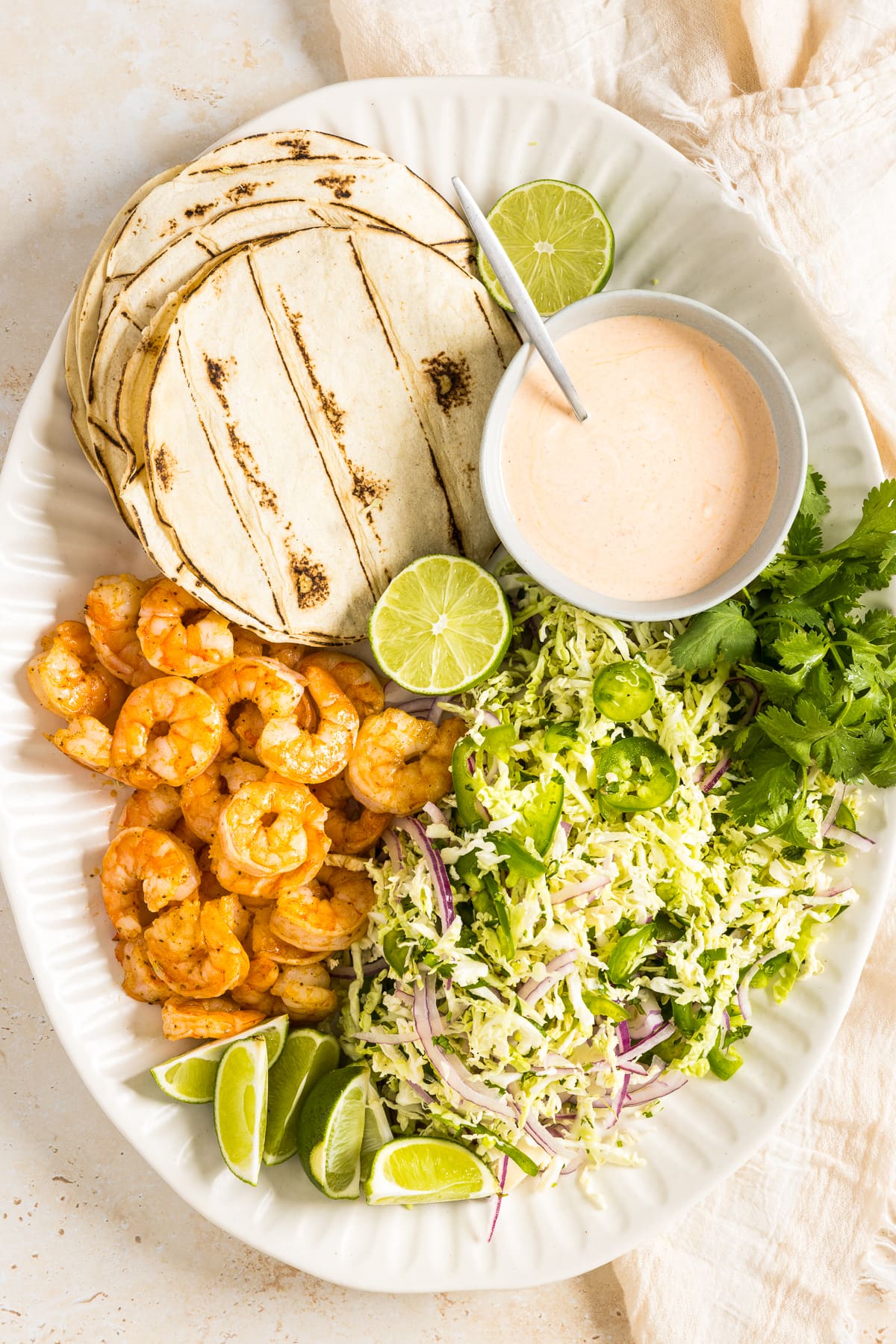 Platter of shrimp, tortillas, coleslaw and shrimp taco sauce