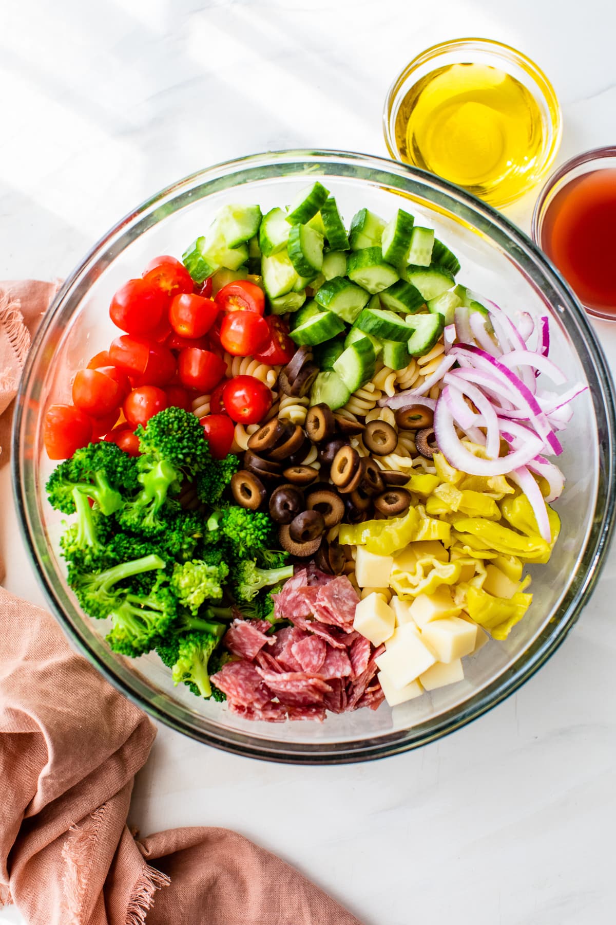 broccoli, tomatoes, and cucumbers, plus Italian favorites, like salami, cheese, pepperoncini, and olives in a bowl.