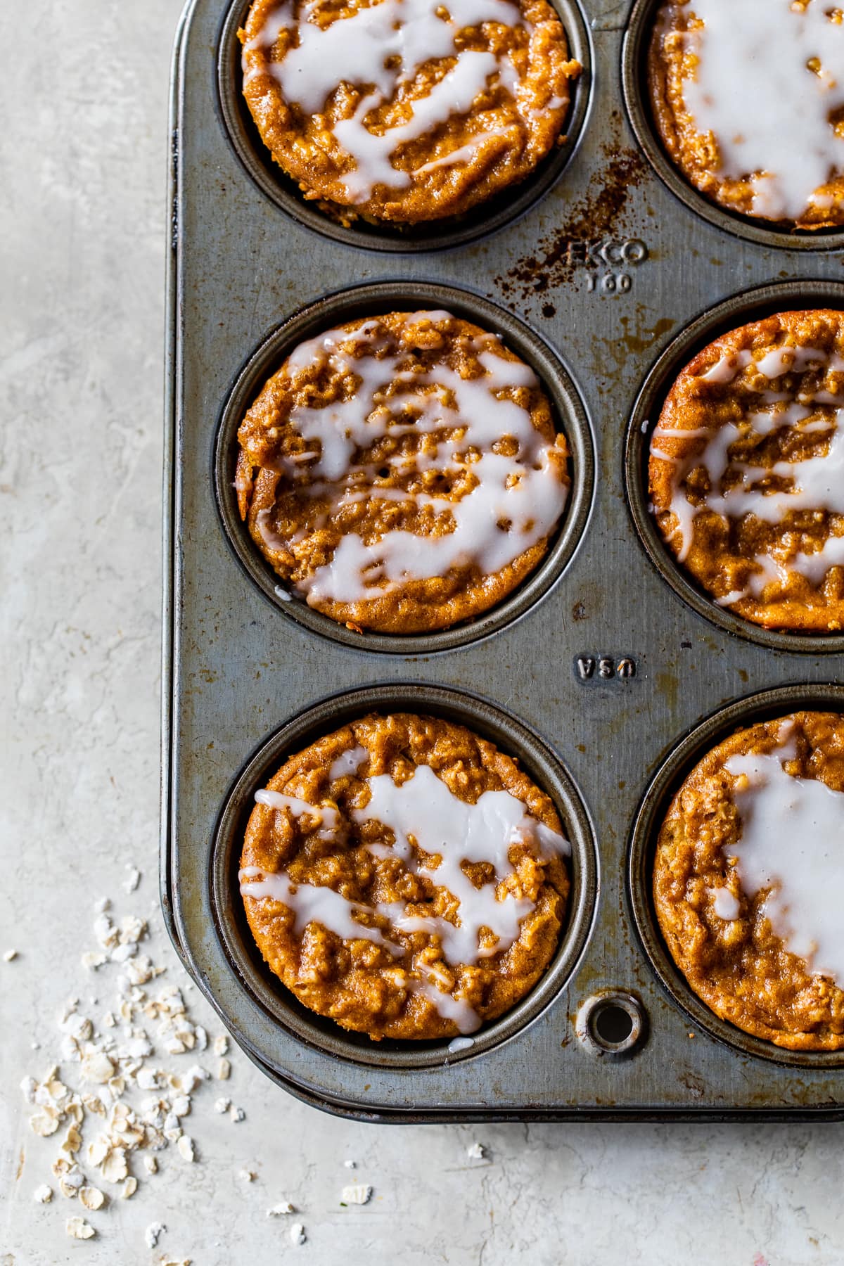 Pumpkin Baked Oatmeal Cups topped with glaze in a muffin pan
