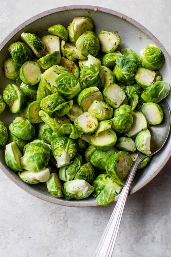Brussel sprouts in a bowl with olive oil and seasoning.