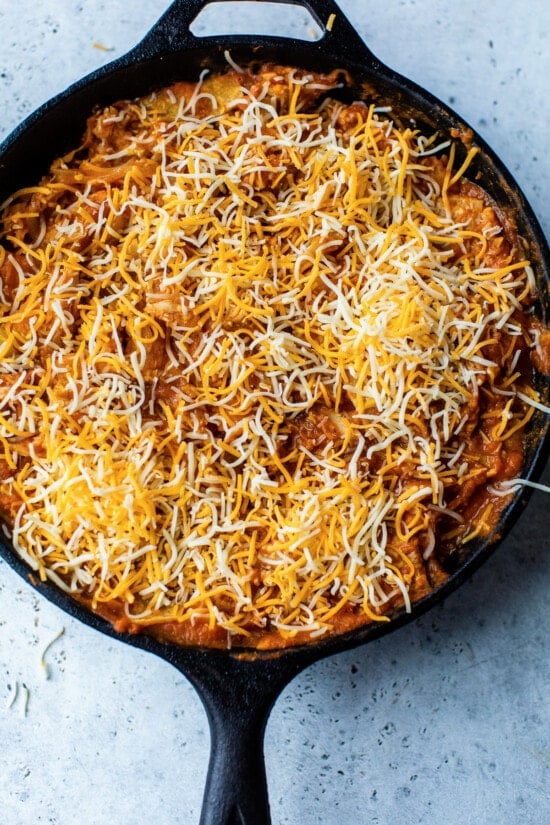 skillet with enchiladas and cheese