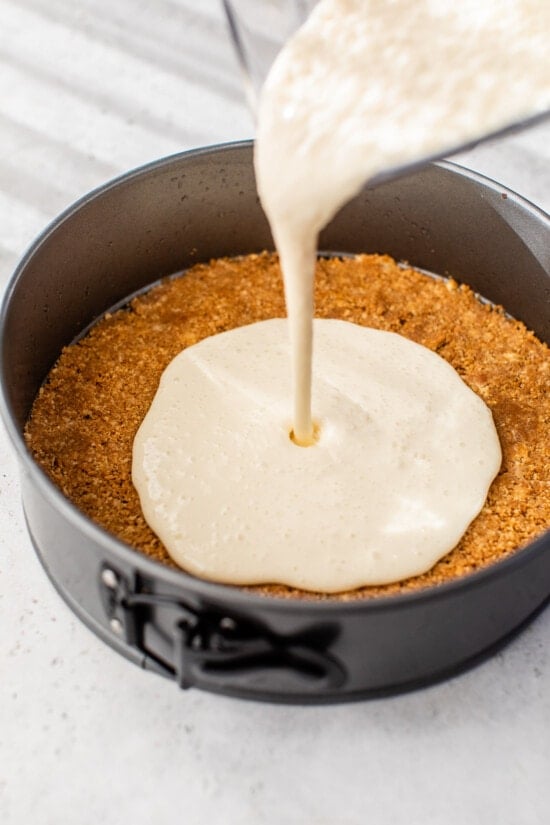pouring the cheesecake batter into the spring pan