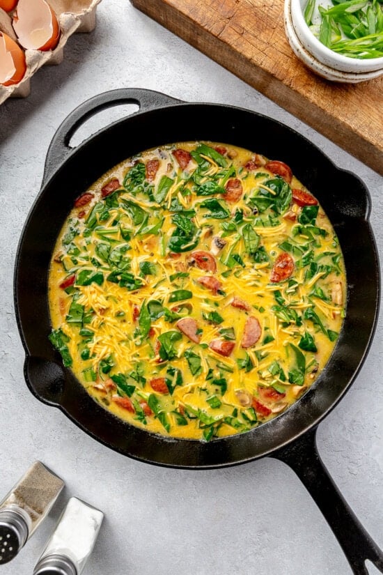 Skillet with smoked sausage, eggs, spinach, mushrooms, and cheese.