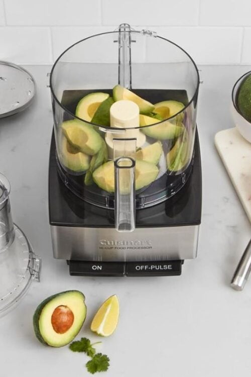 Cuisinart food processor next to accessories and avocados