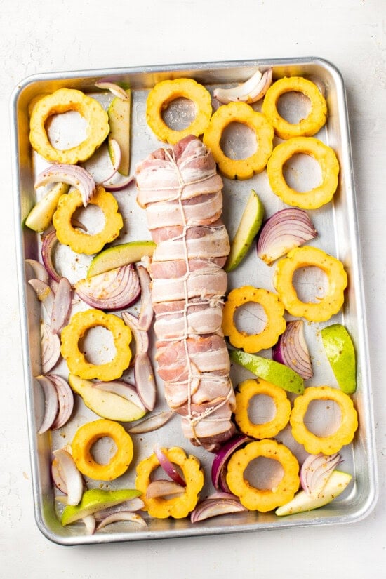 Bacon Wrapped Pork Tenderloin on a sheet pan with fall vegetables